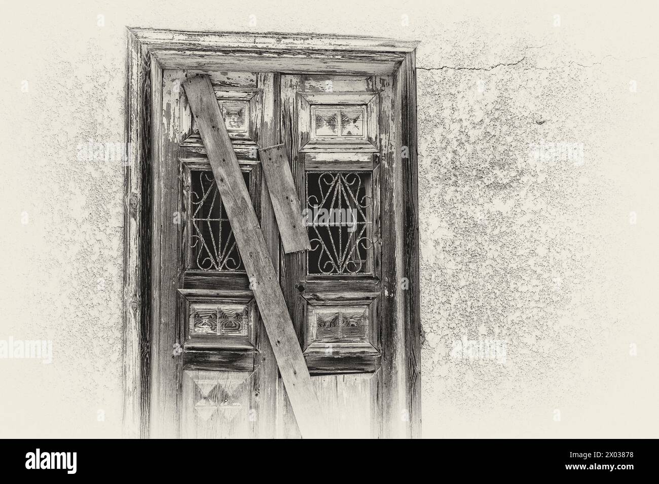 A monochrome filtered image of planks covering a boarded up door on a derelict arabian house in the middle east. Stock Photo