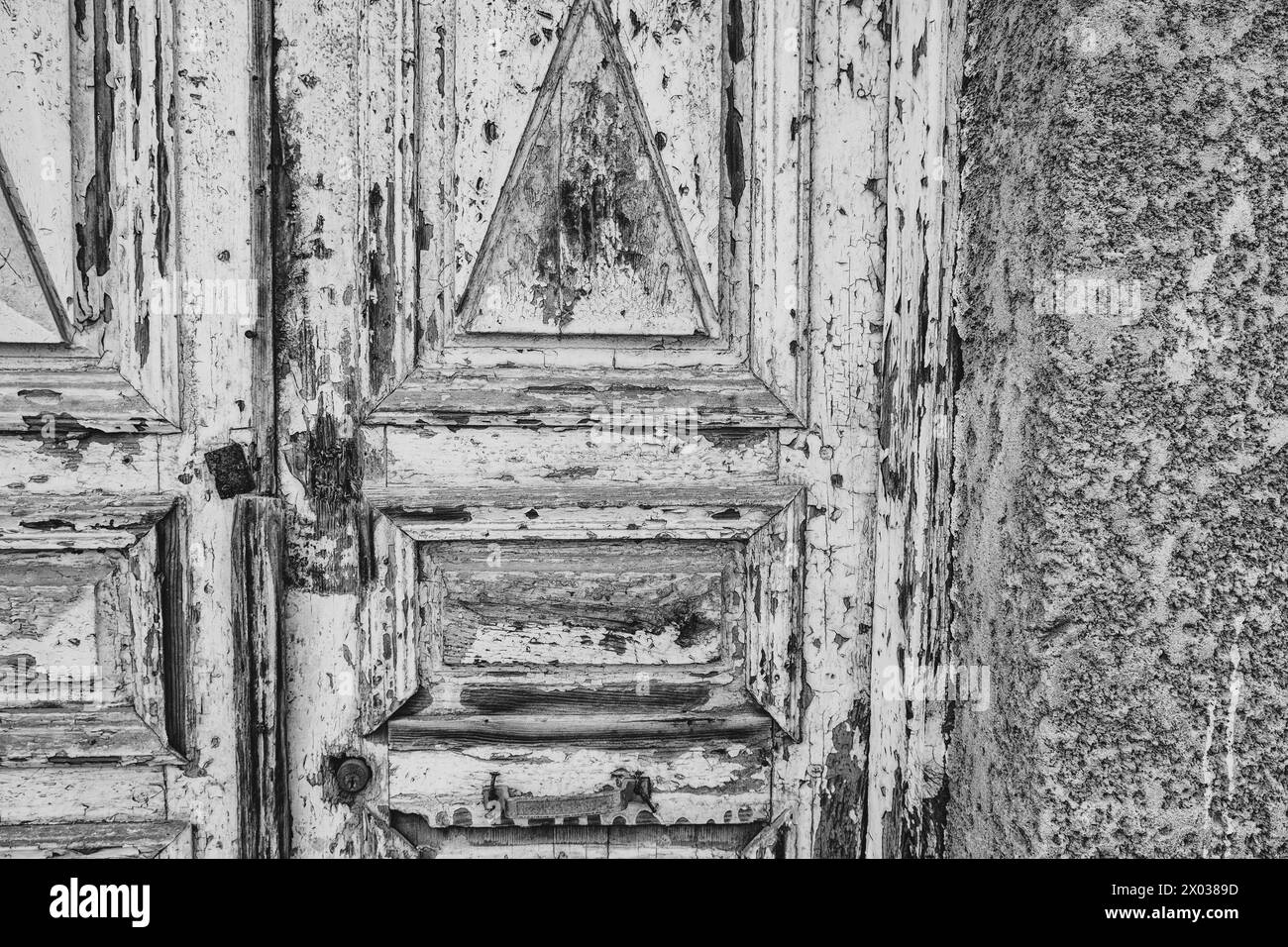 A monochrome view of a weathered wooden door with peeling paint at the entrance to an old arabian house in the Middle East. Stock Photo