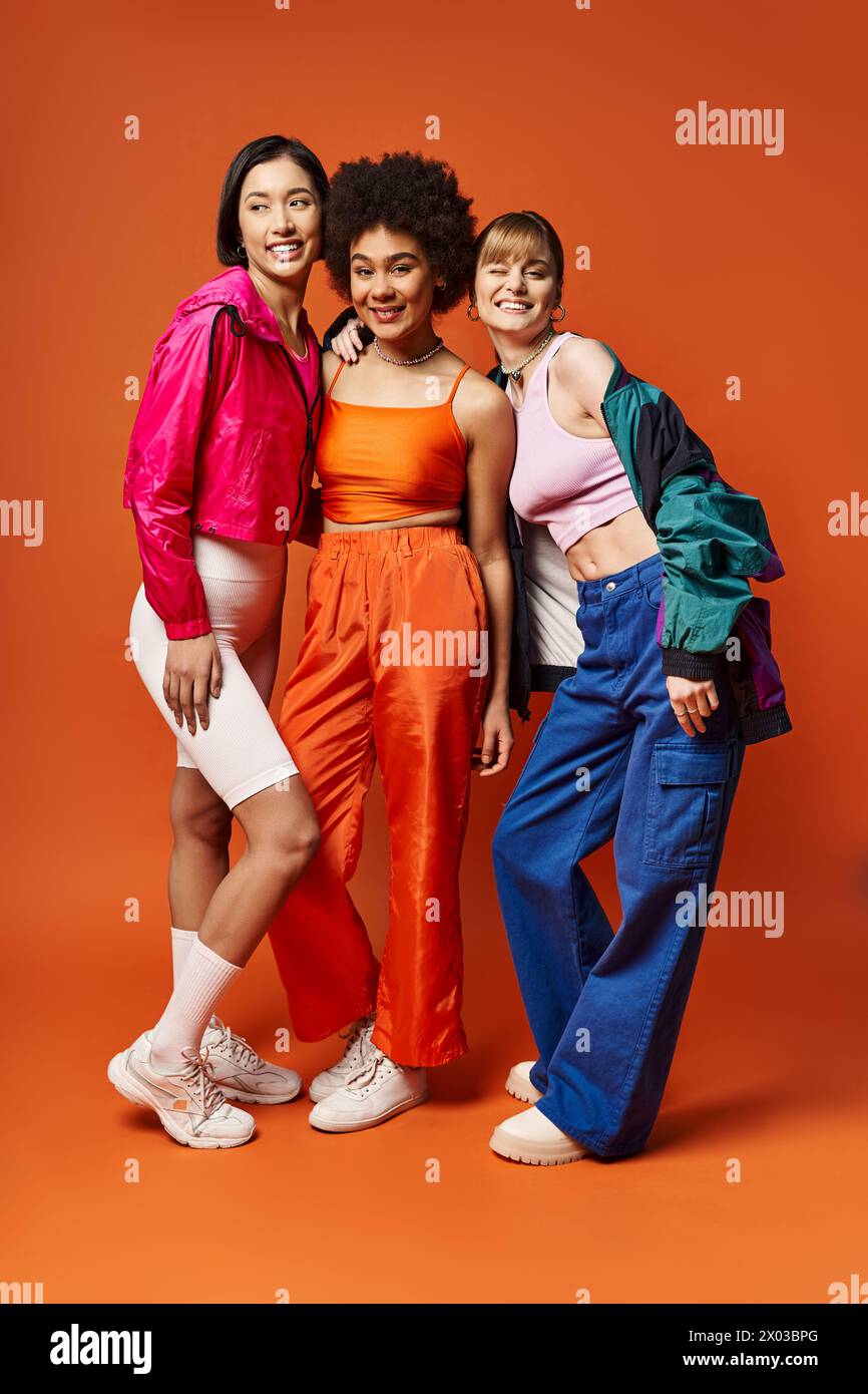 A diverse group of women standing together in front of an orange ...