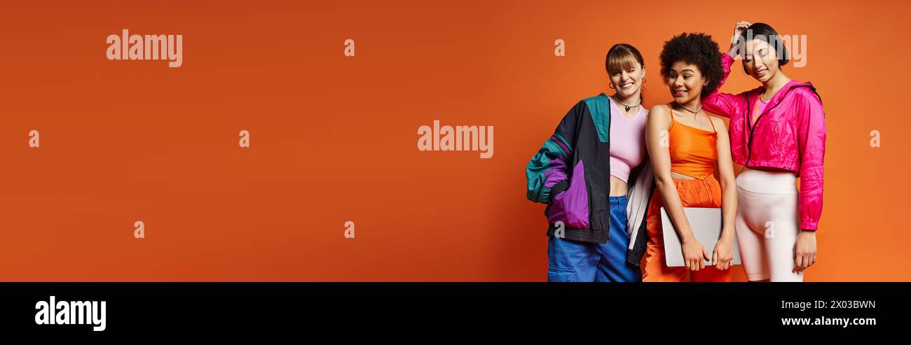 A diverse group of women standing together against an orange studio ...