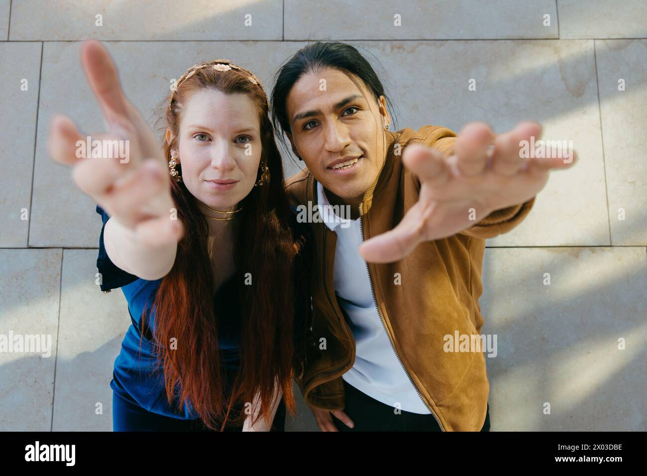 Smiling couple extending hands towards camera with a friendly gesture. Stock Photo