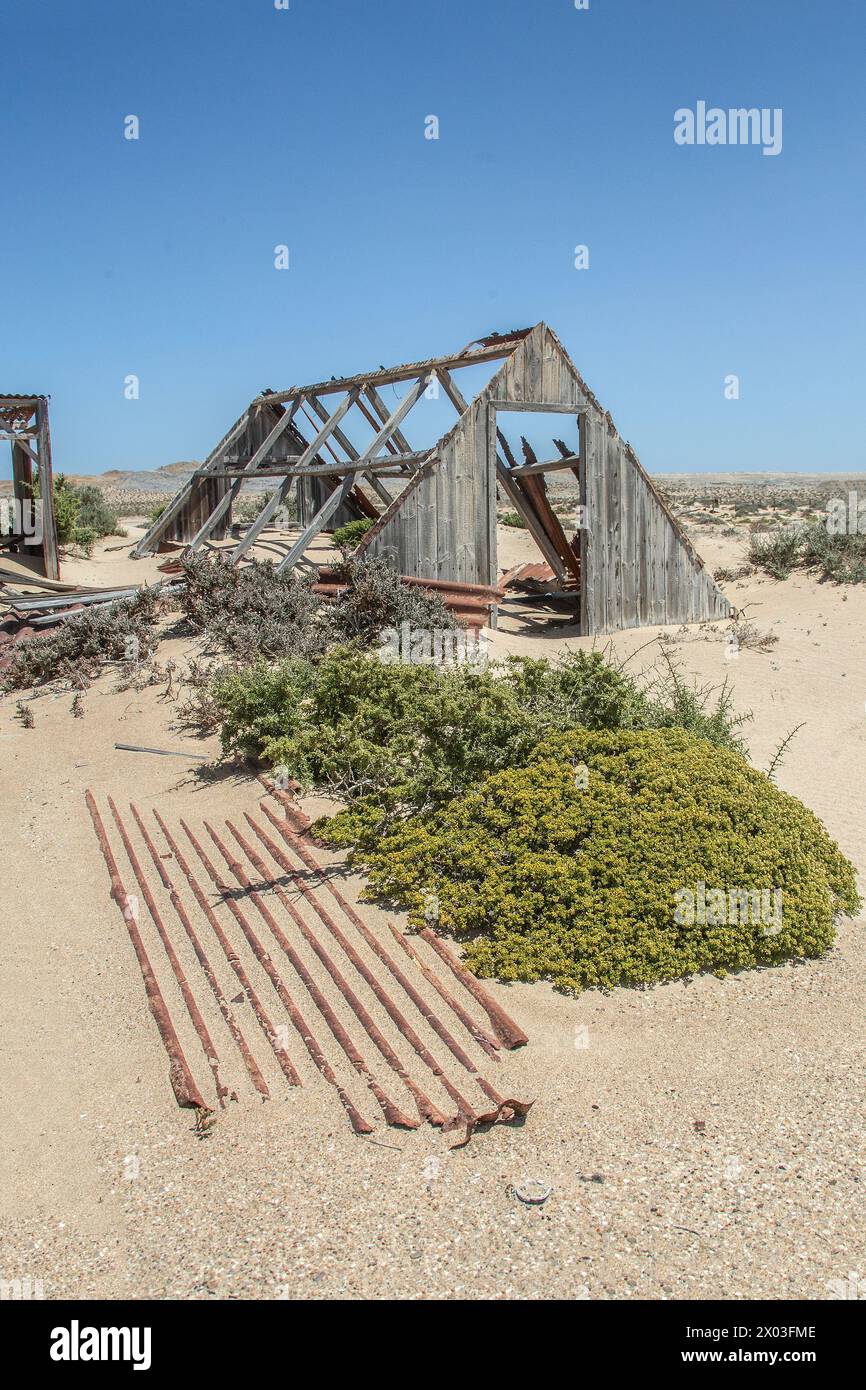 A triangular outhouse, desert vegetation and a corrugated roofing panel at Bogenfels mine in Namibia. Stock Photo