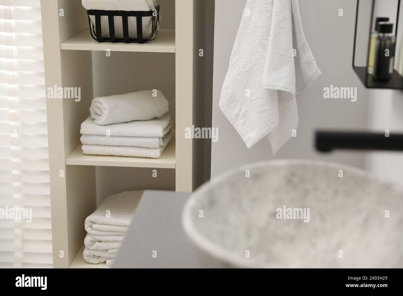 Shelving unit with stacked clean towels in bathroom Stock Photo - Alamy