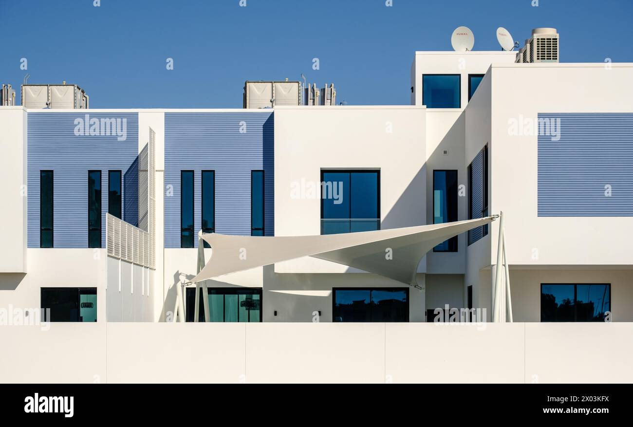 White and blue modern villas in a Middle Eastern, high-end, luxury housing development on a sunny day with strong shadows. Stock Photo