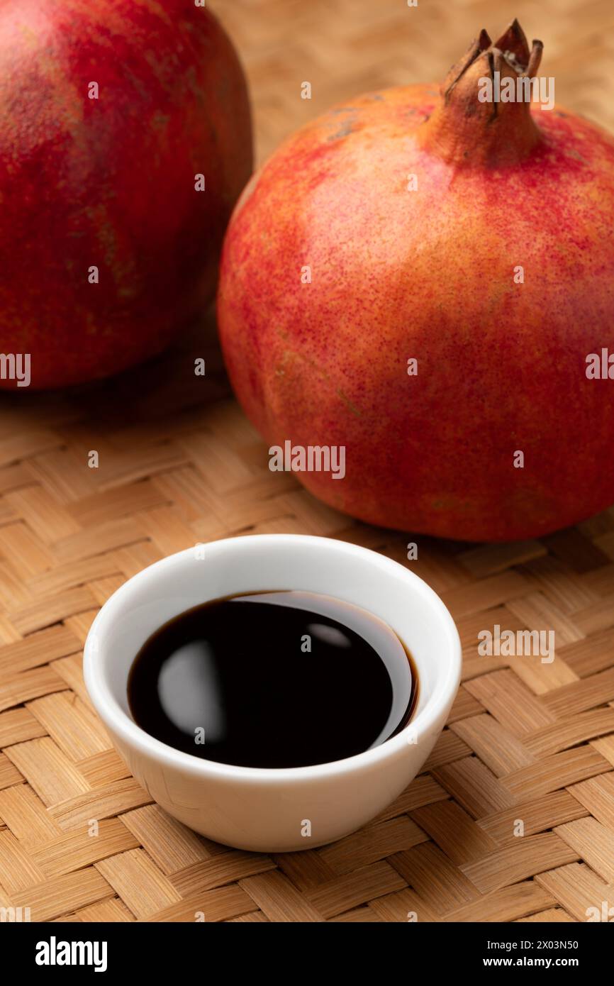 Bowl with traditional pomegranate molasses and fresh pomegranate in the background close up Stock Photo