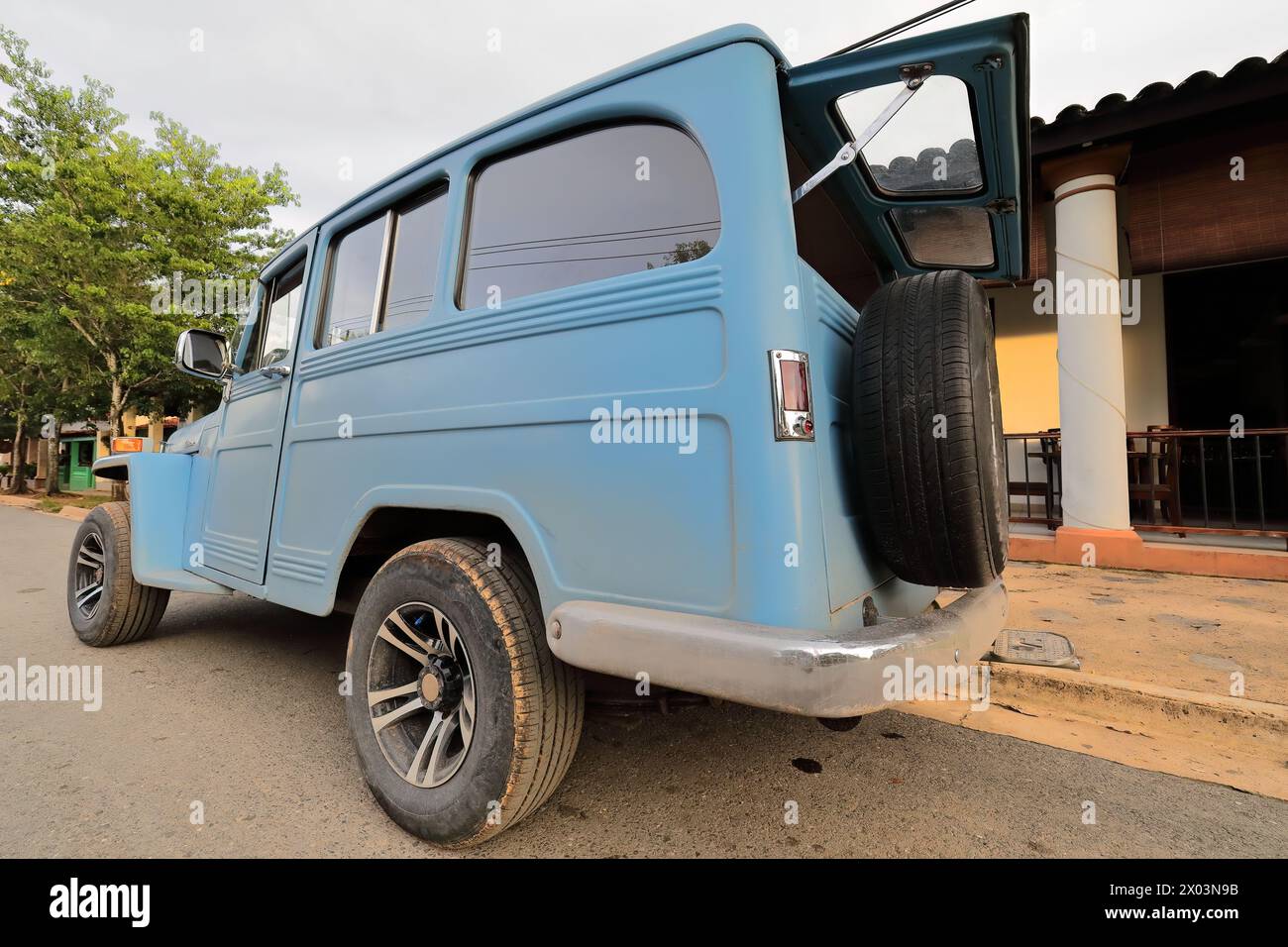 156 Old light blue almendron car -1955 Jeep Willys classic- stationed on a street in the downtown area at the beginning of sunset. Viñales-Cuba. Stock Photo
