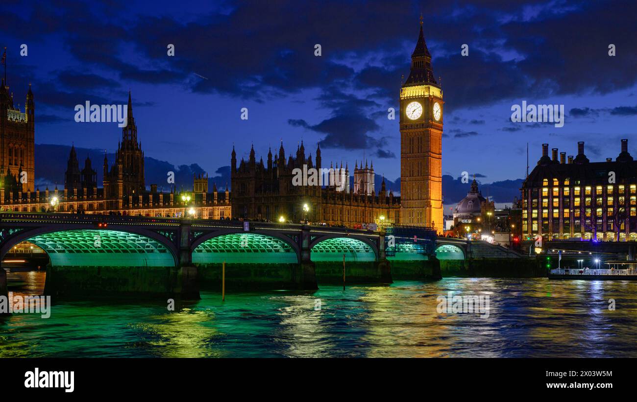 Night at illuminated Westminster Bridge and Elizabeth Tower with reflection in  River Thames Stock Photo