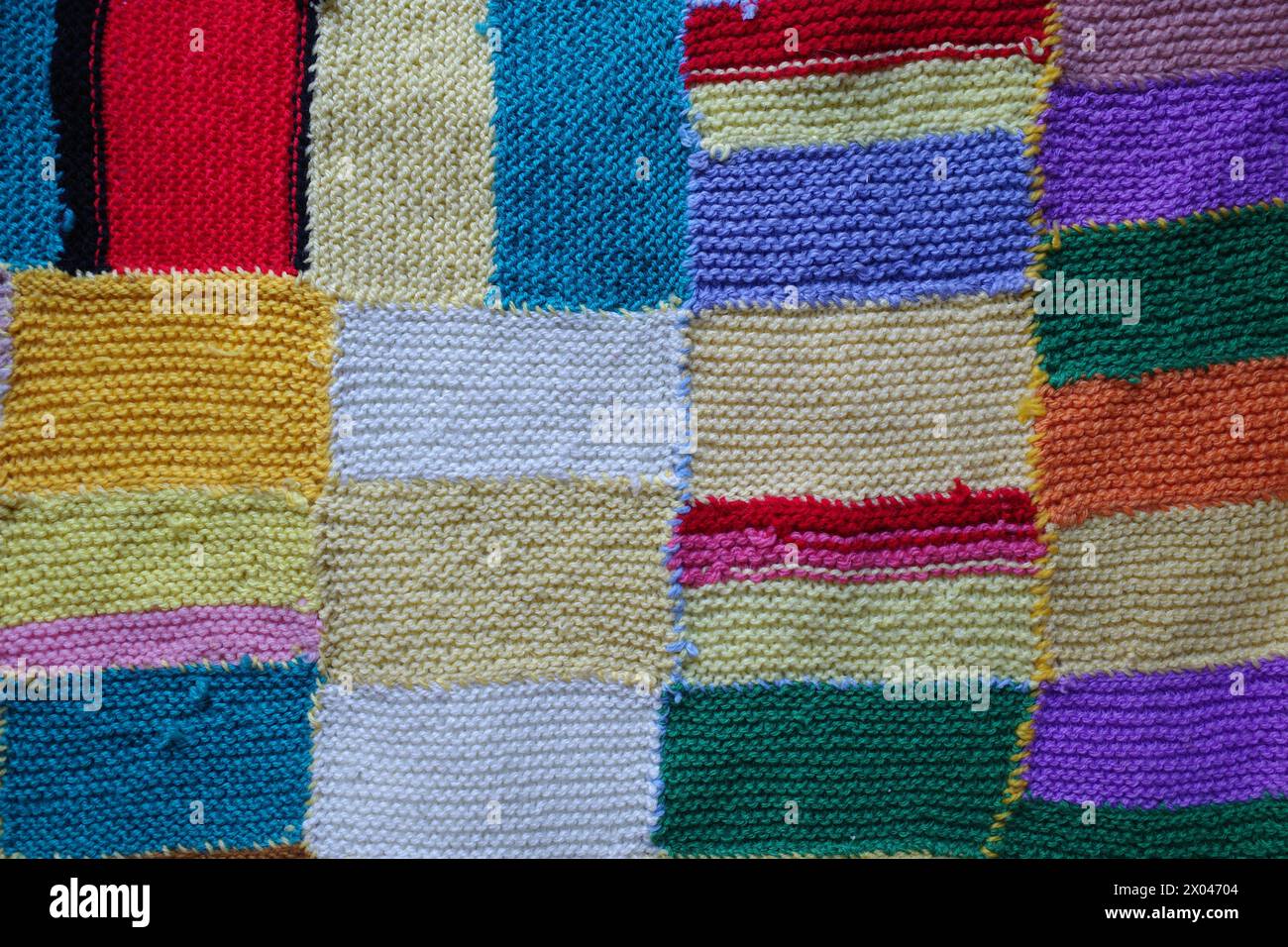 Colorfull knitted patchwork blanket stitched together. Stock Photo