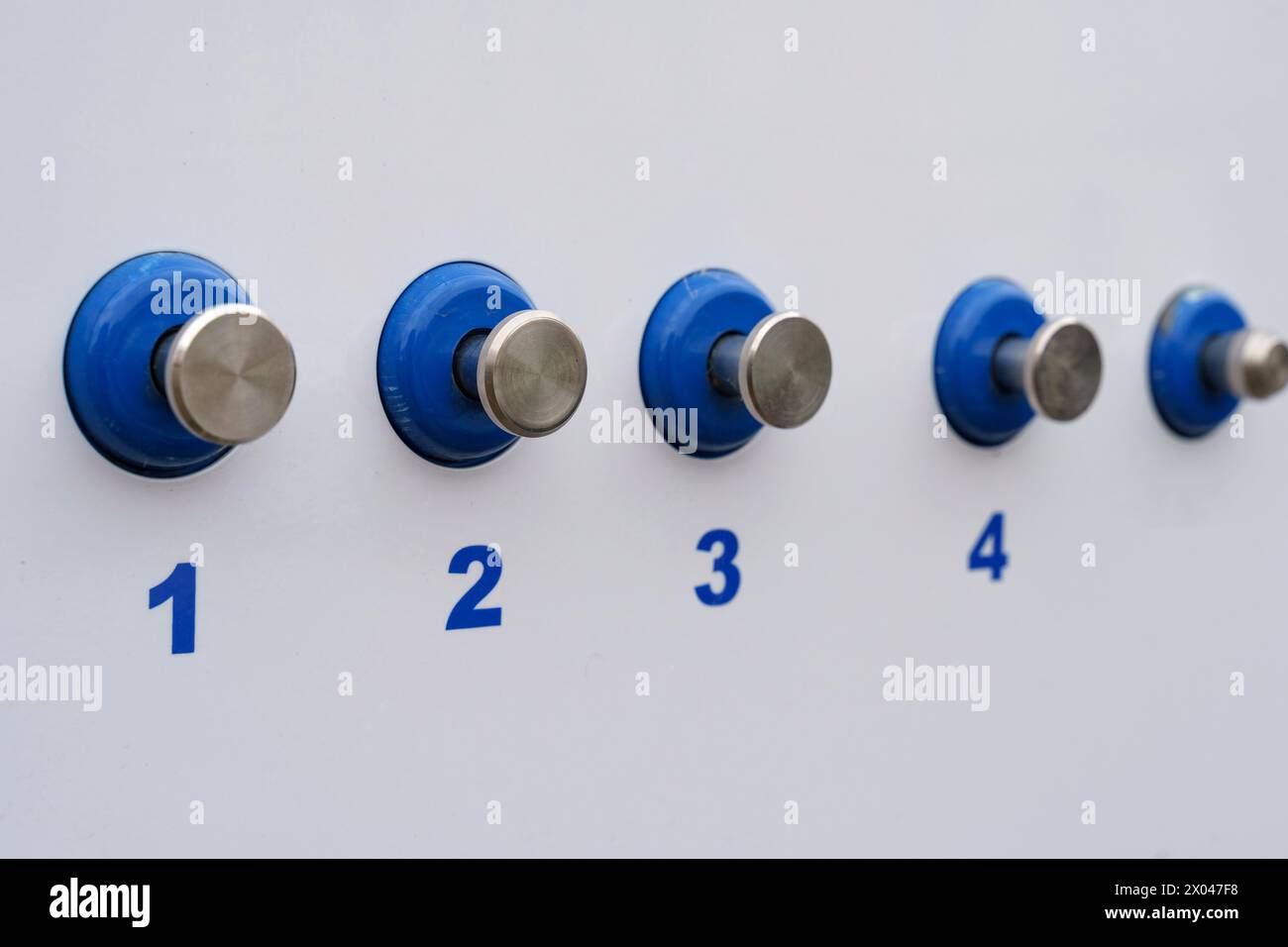 Blue and silver knobs are mounted on a clean white wall, creating a modern and stylish look. Stock Photo