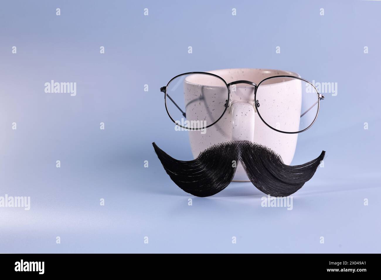 Man's face made of artificial mustache, glasses and cup on light blue background. Space for text Stock Photo