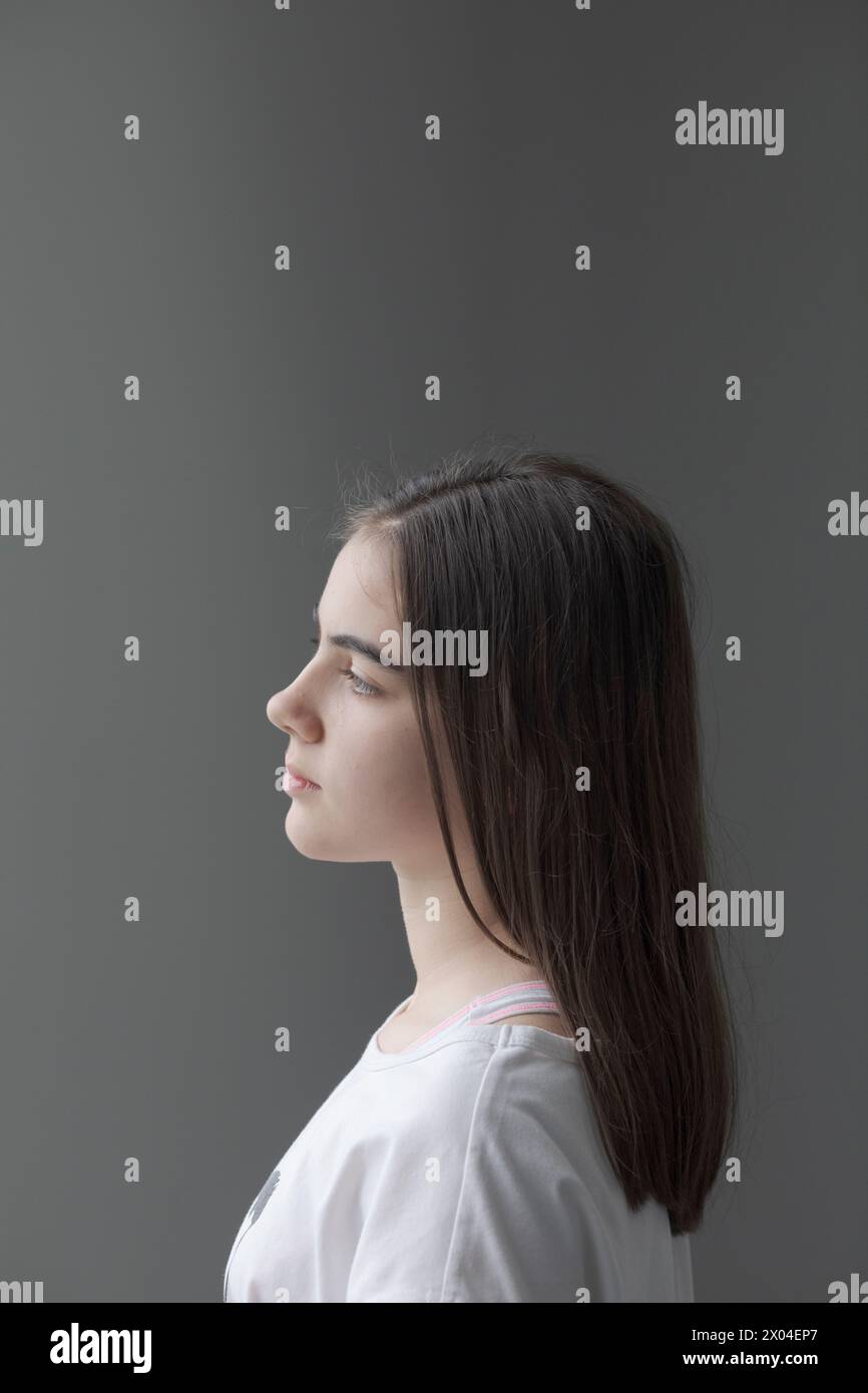 Vertical portrait with white background of a teenage girl in profile ...
