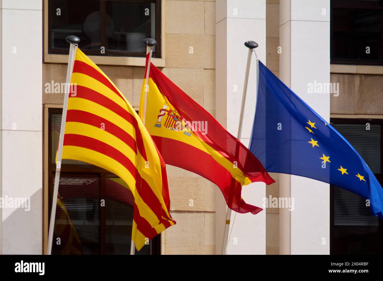 The flags of Spain, Catalonia, and Europe fluttering in the wind, symbolizing unity, diversity, and coexistence in the European community. Stock Photo