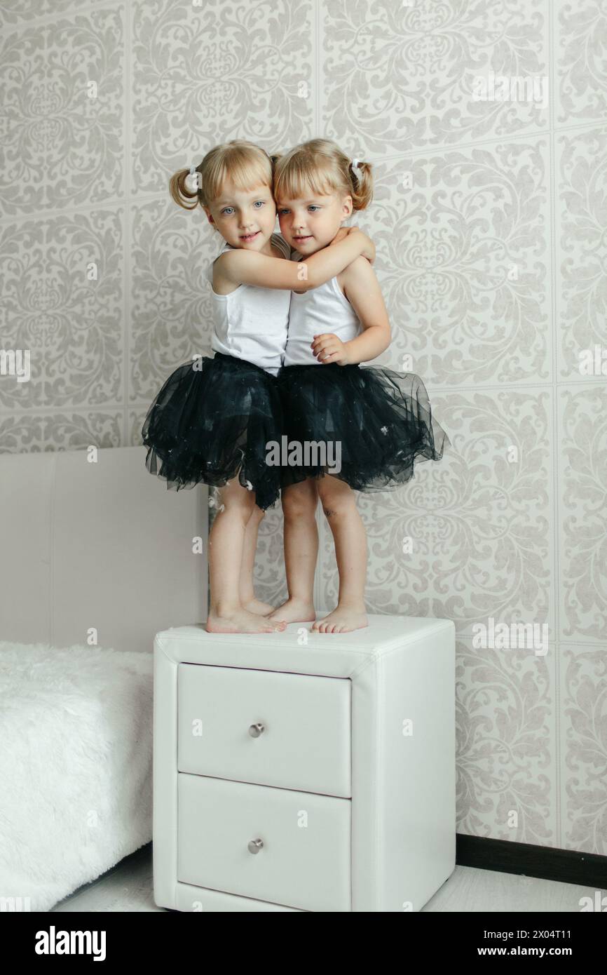Two young girls embracing each other tightly while standing on top of a ...