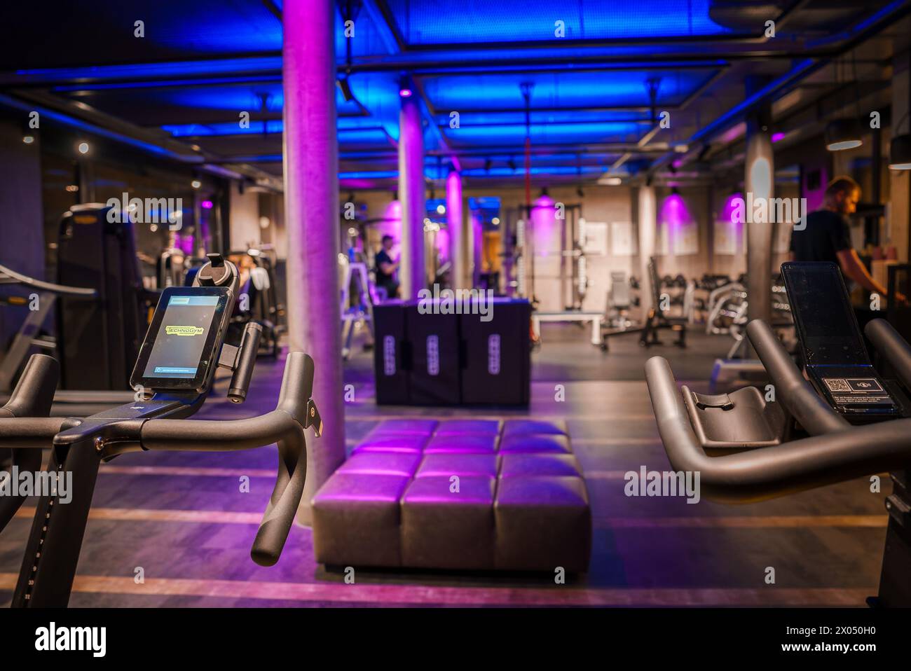 Modern Gym with Cardio Equipment, Purple Lighting and Exposed Ductwork Stock Photo