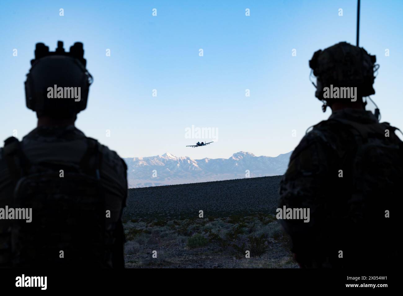 U.S. Air Force Capt. Jason Hoist, a 422nd Test and Evaluation Squadron (TES) Tactical Air Control Party (TACP) officer, left, and Staff Sgt. Matthew Gutierrez, a 422nd TES TACP specialist, watch an A-10 Thunderbolt II fly over the Nevada Test and Training Range during Joint Terminal Attack Controller proficiency training, April 2, 2024. Tactical Air Control Party specialists utilize advanced radio skills and aircraft ordnance knowledge when calling in precise airstrikes. (U.S. Air Force photo by Senior Airman Jose Miguel T. Tamondong) Stock Photo