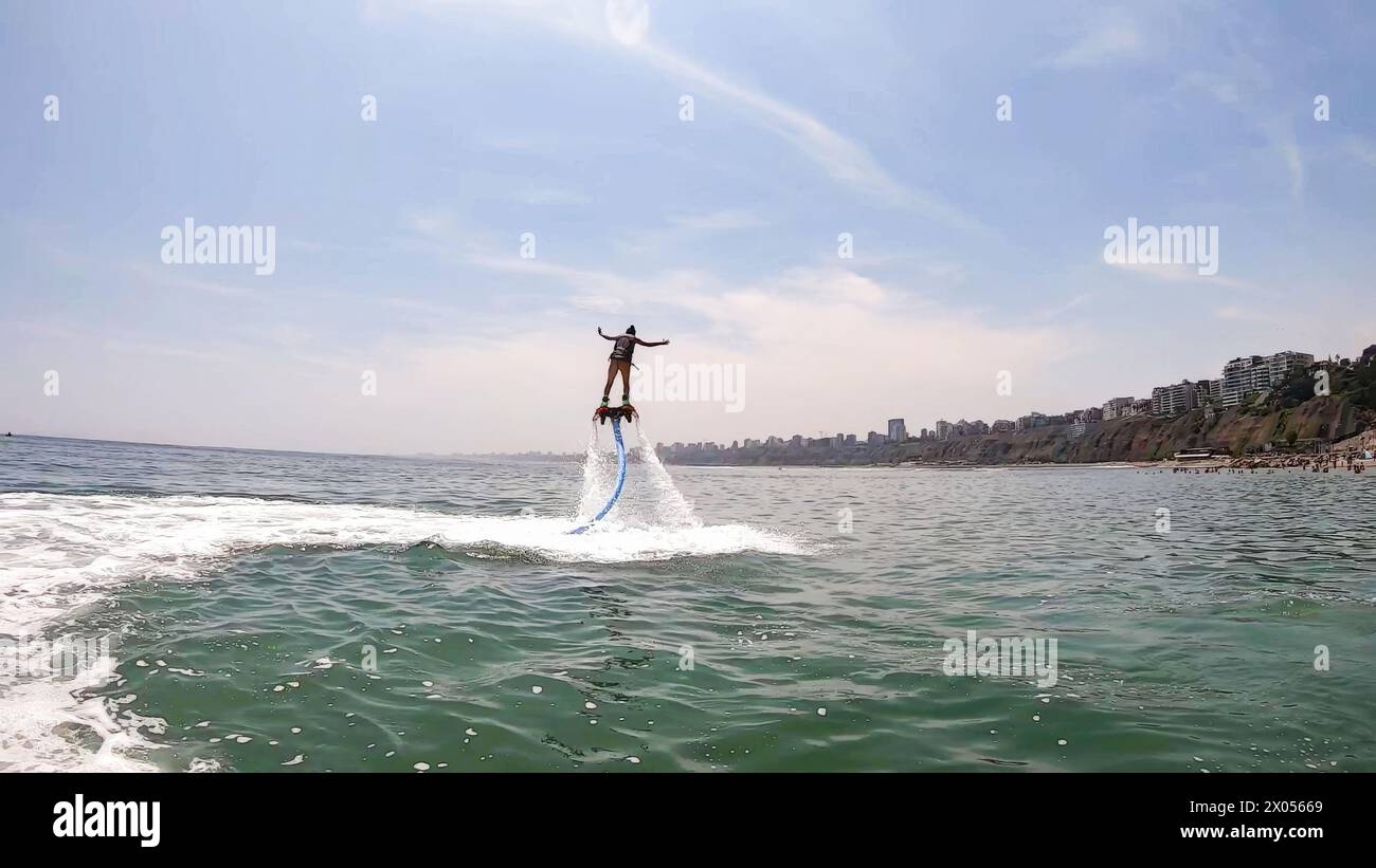 Exhilarating scene of a person using a water-propelled jet pack on a sunny day by the beach Stock Photo