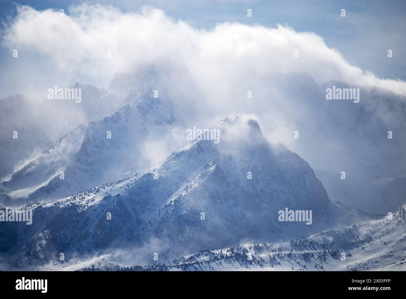 clouds and snow blowing around the summit of the Sierra Nevada Mountains west of Bishop California Stock Photo