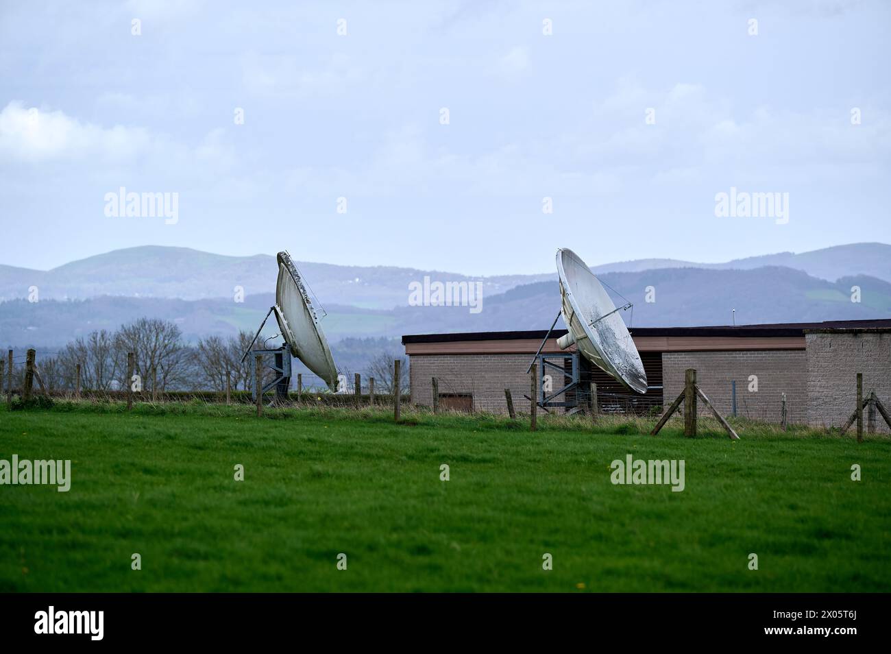 Two old satellite dishes in green field in England Stock Photo