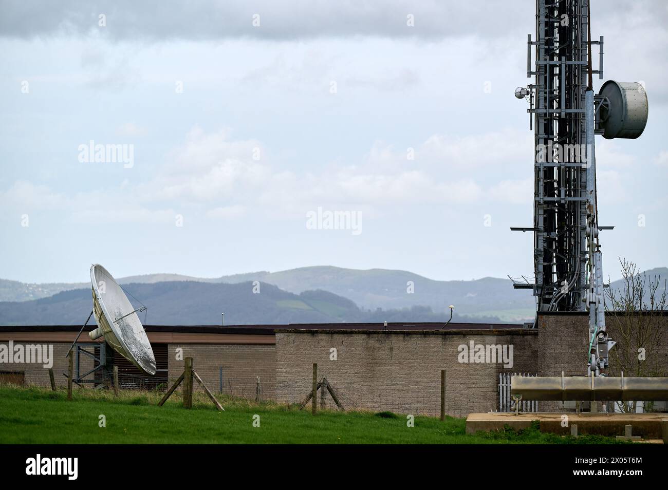 An old satellite dish in green field in England with part of radio mast Stock Photo