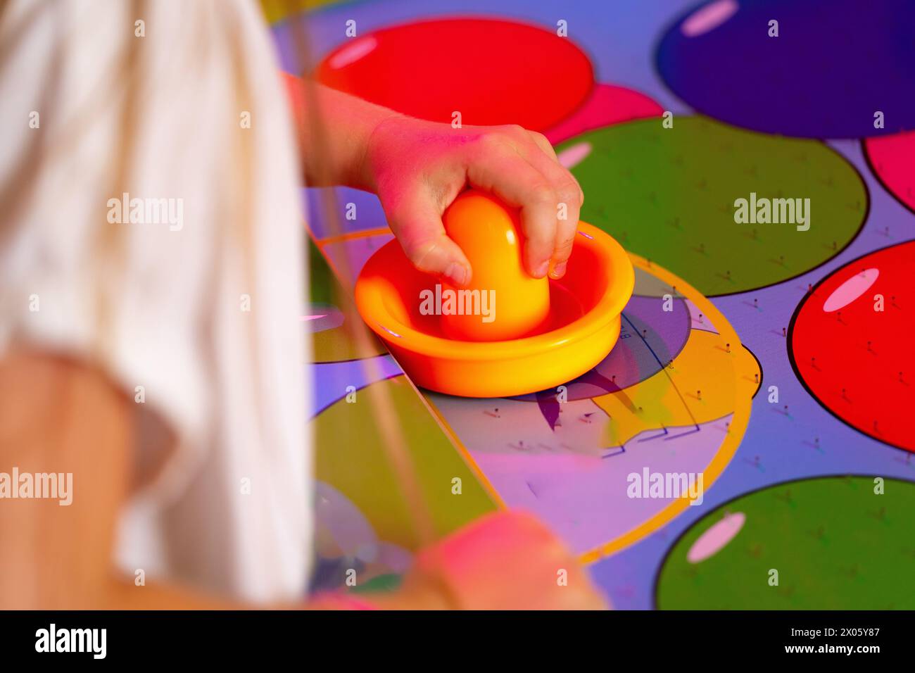 Young Child Playing Twister Game With Colorful Spinner on Bright Mat Stock Photo