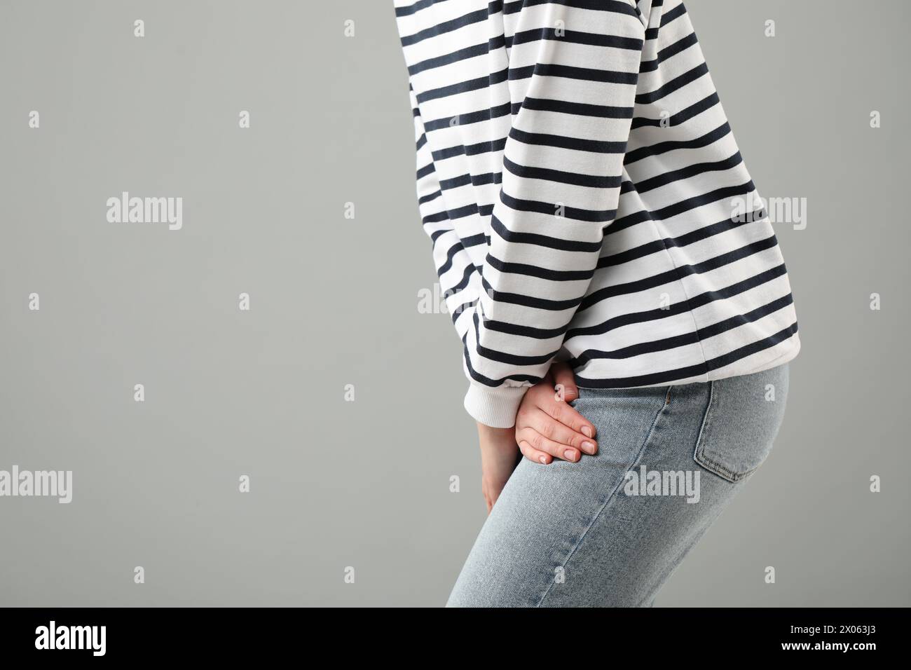 Woman suffering from cystitis on grey background, closeup. Space for text Stock Photo