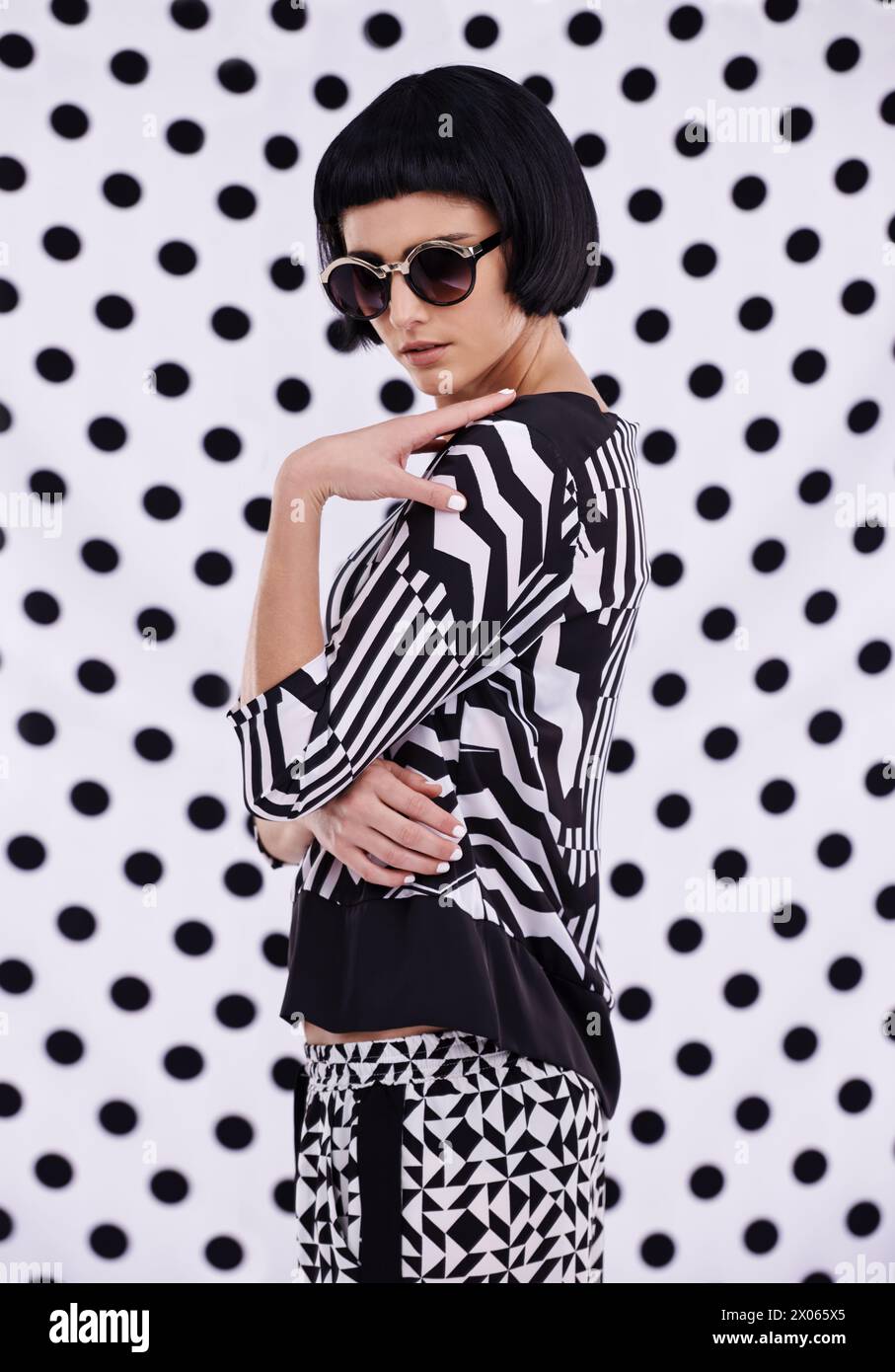 Fashion, retro or woman on polka dot or white background in trendy stylish outfit or vintage sunglasses. Unique, monochrome and confident female model Stock Photo