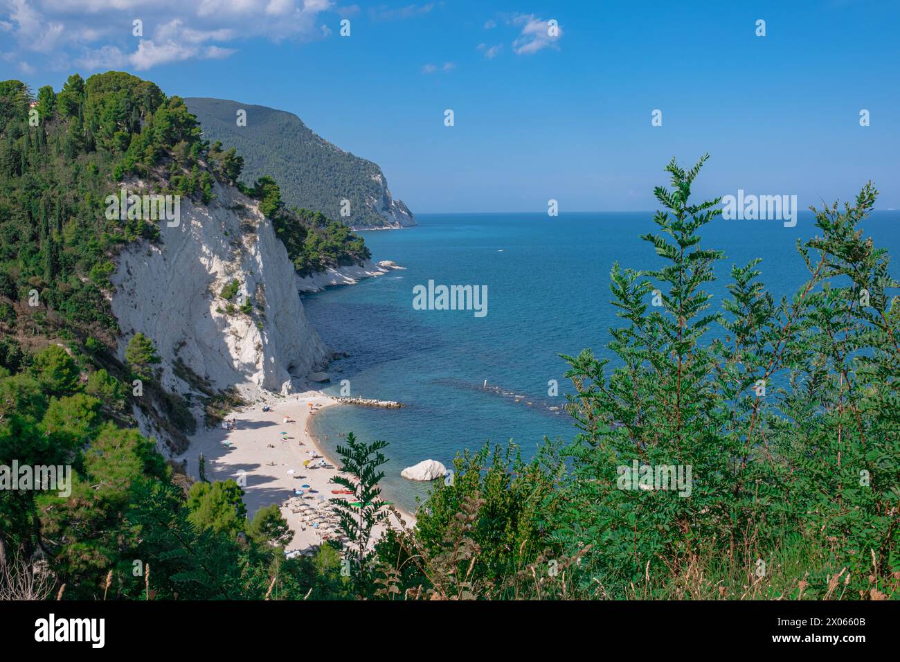 Beach of the Two Sisters in Italy, Numana. Beautiful view of the popular sea beach. Pines and other vegetation on the shore and blue water, and above Stock Photo