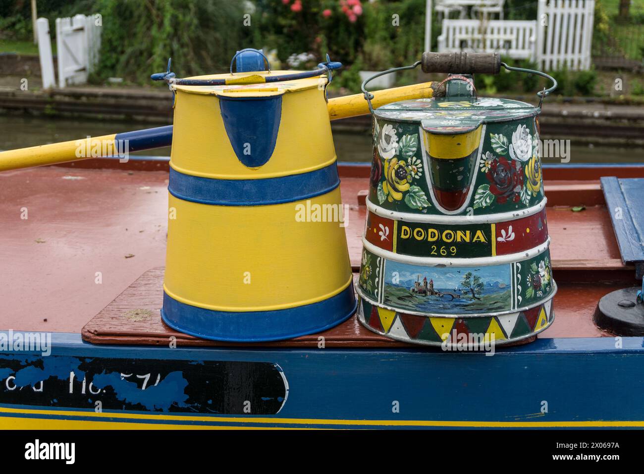 Buckby watering cans decorated in Roses and Castles canal art, on a narrowboat at Stoke Bruerne, Northamptonshire, UK Stock Photo