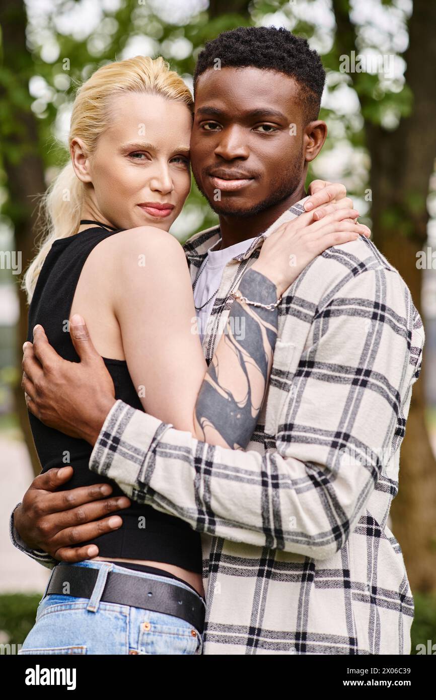 A joyful moment in a park as a multicultural couple, an African American man and Caucasian woman, embrace each other. Stock Photo