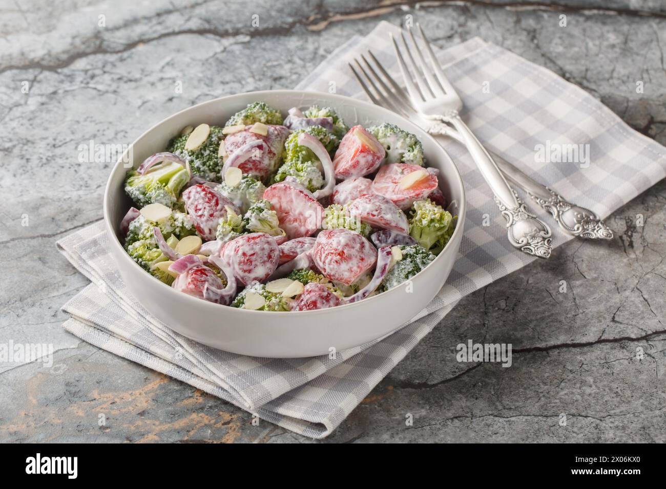 Broccoli salad with fresh strawberries, red onion, almonds and Greek yogurt close-up in a plate on the table. Horizontal Stock Photo