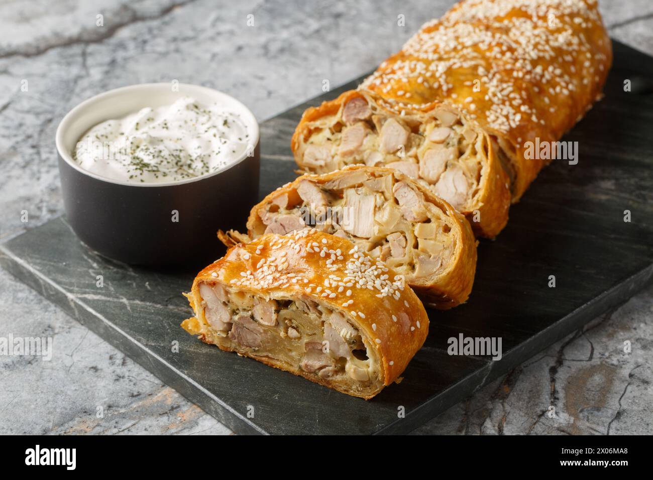 Strudel pie with chicken, mushrooms and cheese served with sauce close-up on a board on the table. Horizontal Stock Photo
