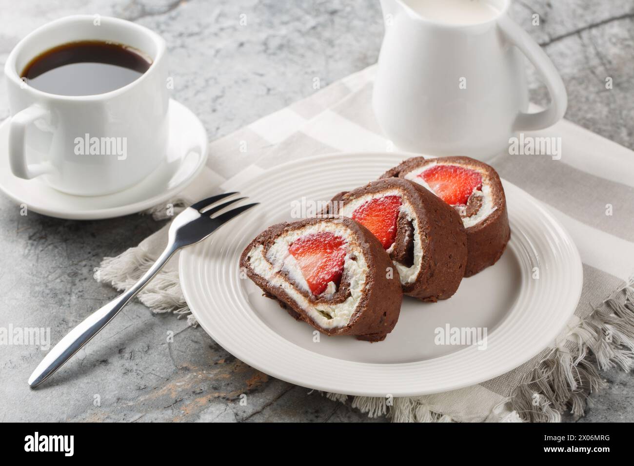 Chocolate cake roll with fresh strawberries and cream cheese closeup on a marble background. Horizontal Stock Photo