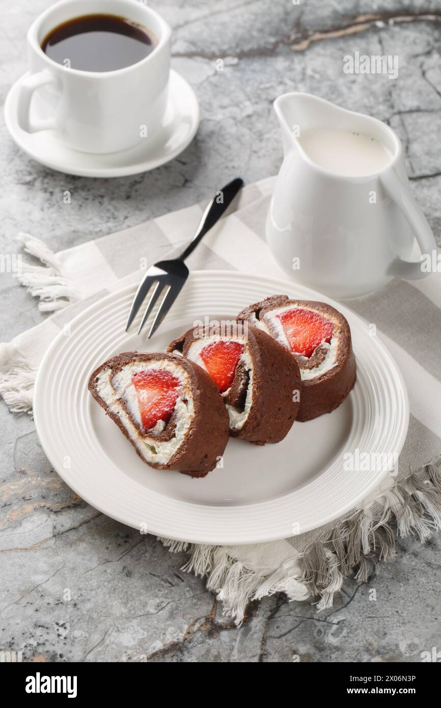 Strawberry chocolate Swiss roll cheesecake served with coffee close-up on the table. Vertical Stock Photo