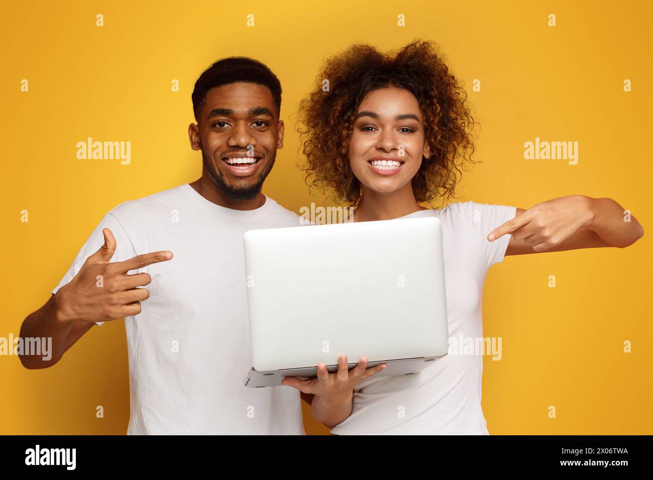 Happy african american couple showing their new laptop Stock Photo - Alamy