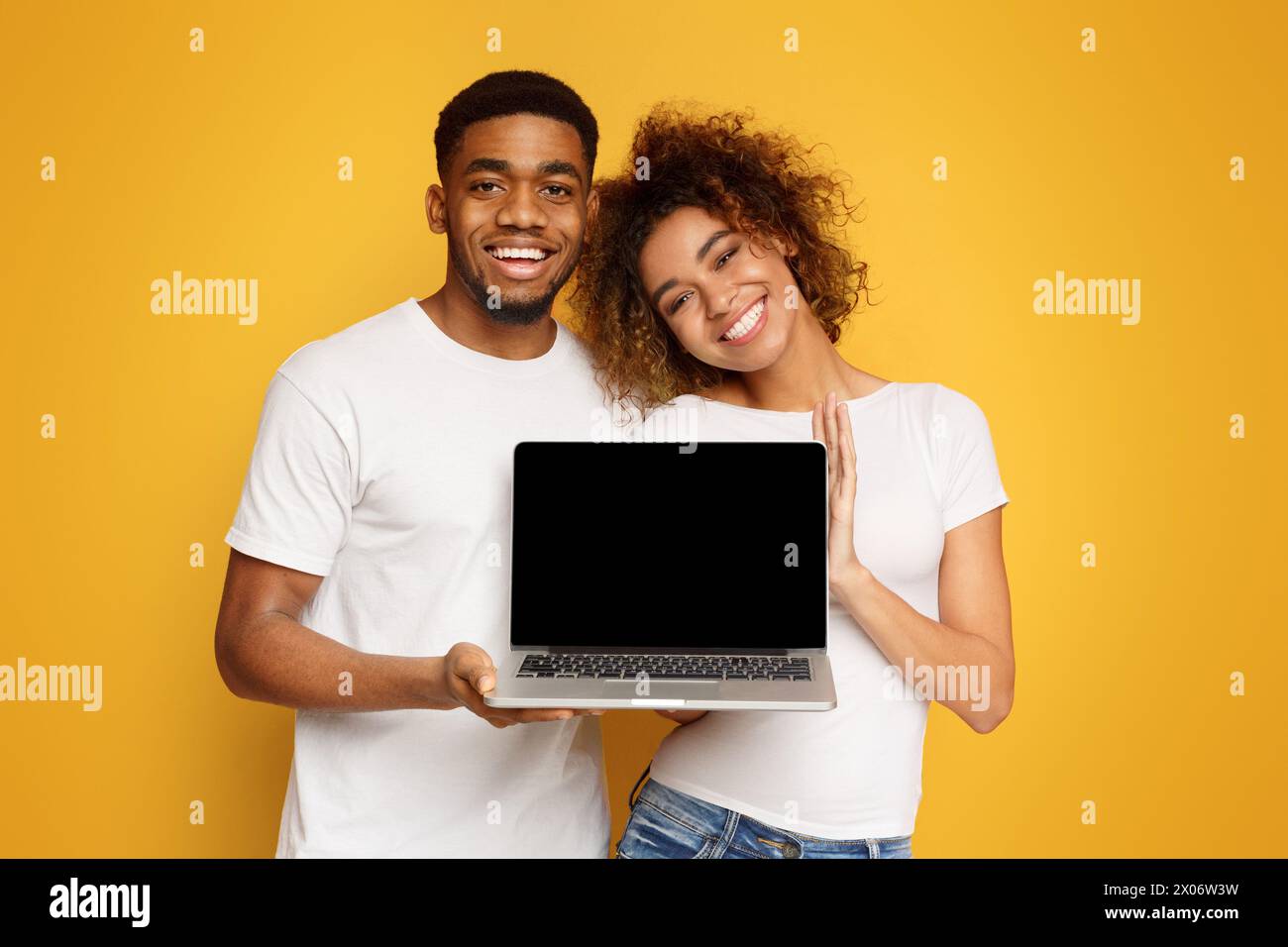 Young black couple holding laptop with blank screen Stock Photo - Alamy