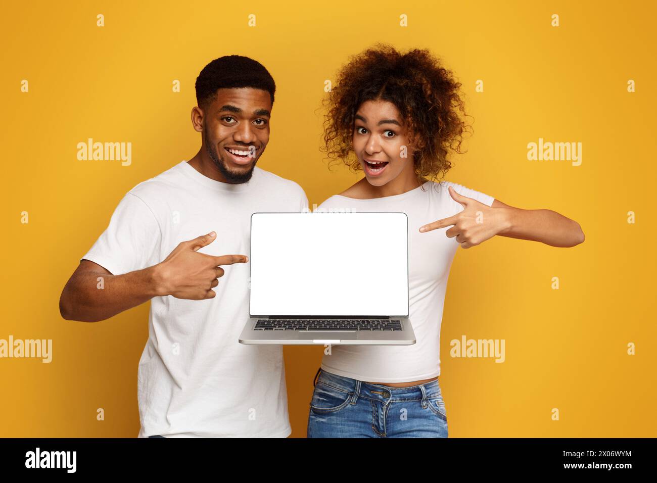 Positive african couple pointing at blank laptop screen Stock Photo - Alamy