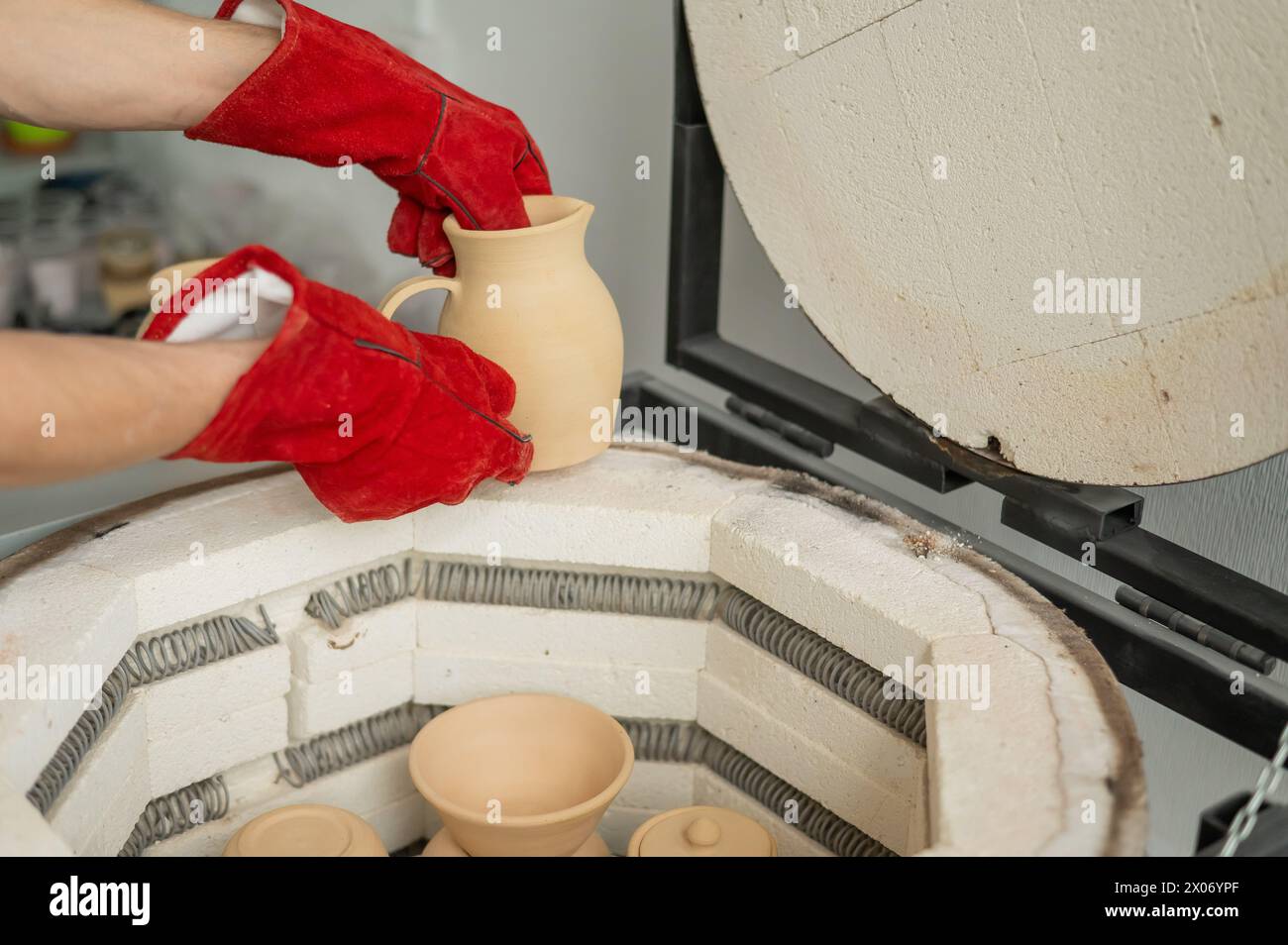 Close-up of a man's hands loading ceramics into a special kiln Stock ...