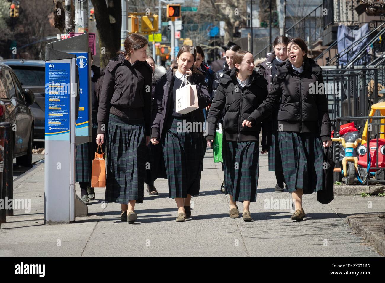 Classmates in matching school uniforms leave classes on a mild spring Sunday. In Brooklyn, New York. Stock Photo