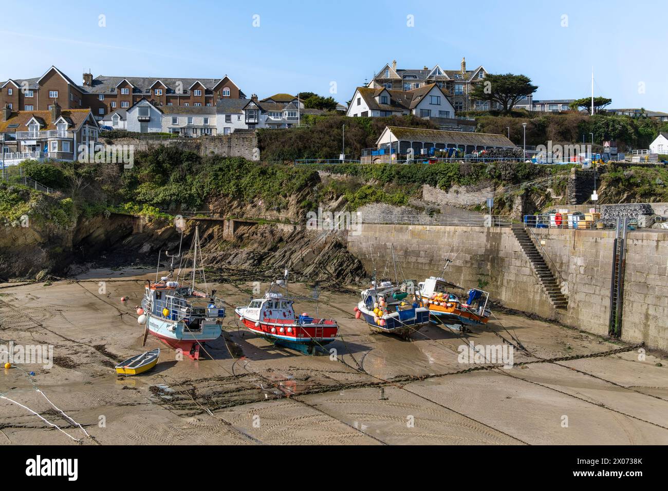 Fishing boats tied up in the quaint historic tidal harbour In Newquay in Cornwall in the UK. Stock Photo