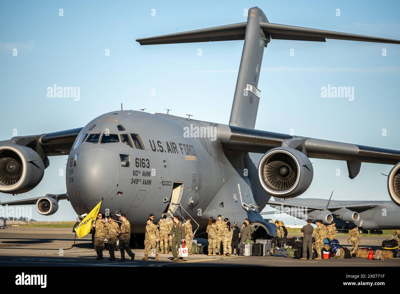 U.S. Airmen with the 21st Airlift Squadron greet and unload equipment from a C-17 Globemaster III on the flightline at Travis Air Force Base Stock Photo