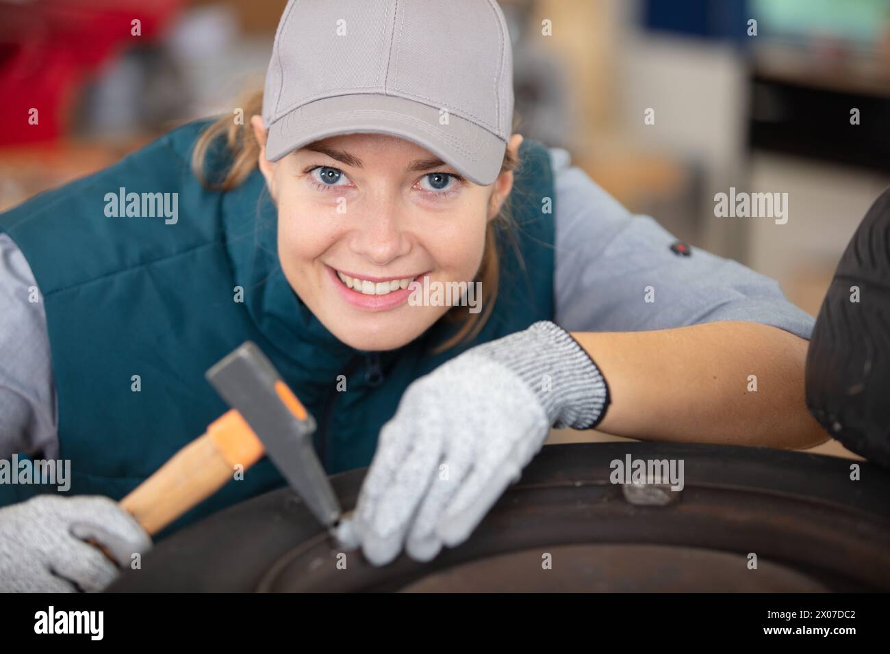 female mechanic using a hammer while working on a tyre Stock Photo