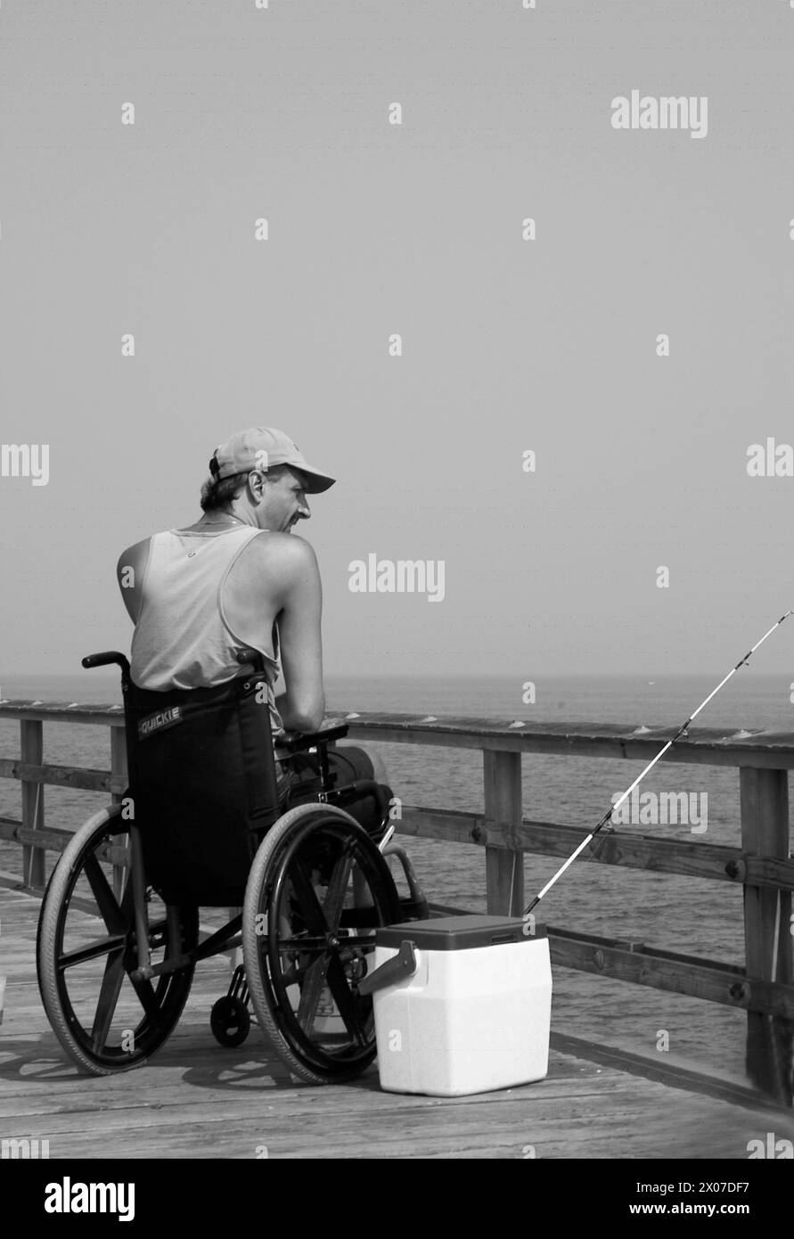 Man in wheelchair fishes at Chesapeake Bay Virginia USA Stock Photo