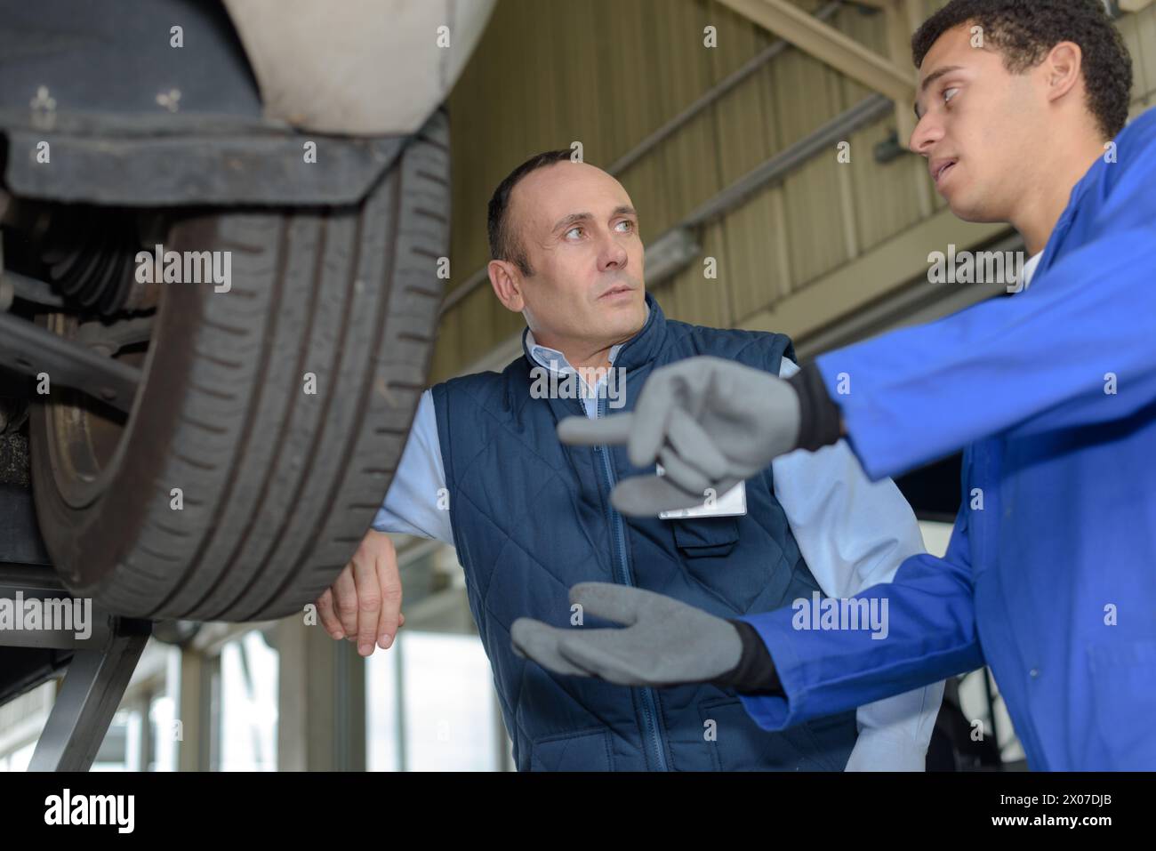 mechanic asking supervisor a question about car wheel Stock Photo
