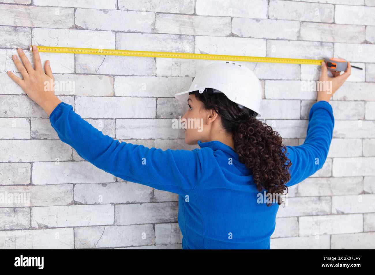 Builders Using Measure female builder use tape measure to inspect building construction Stock ...