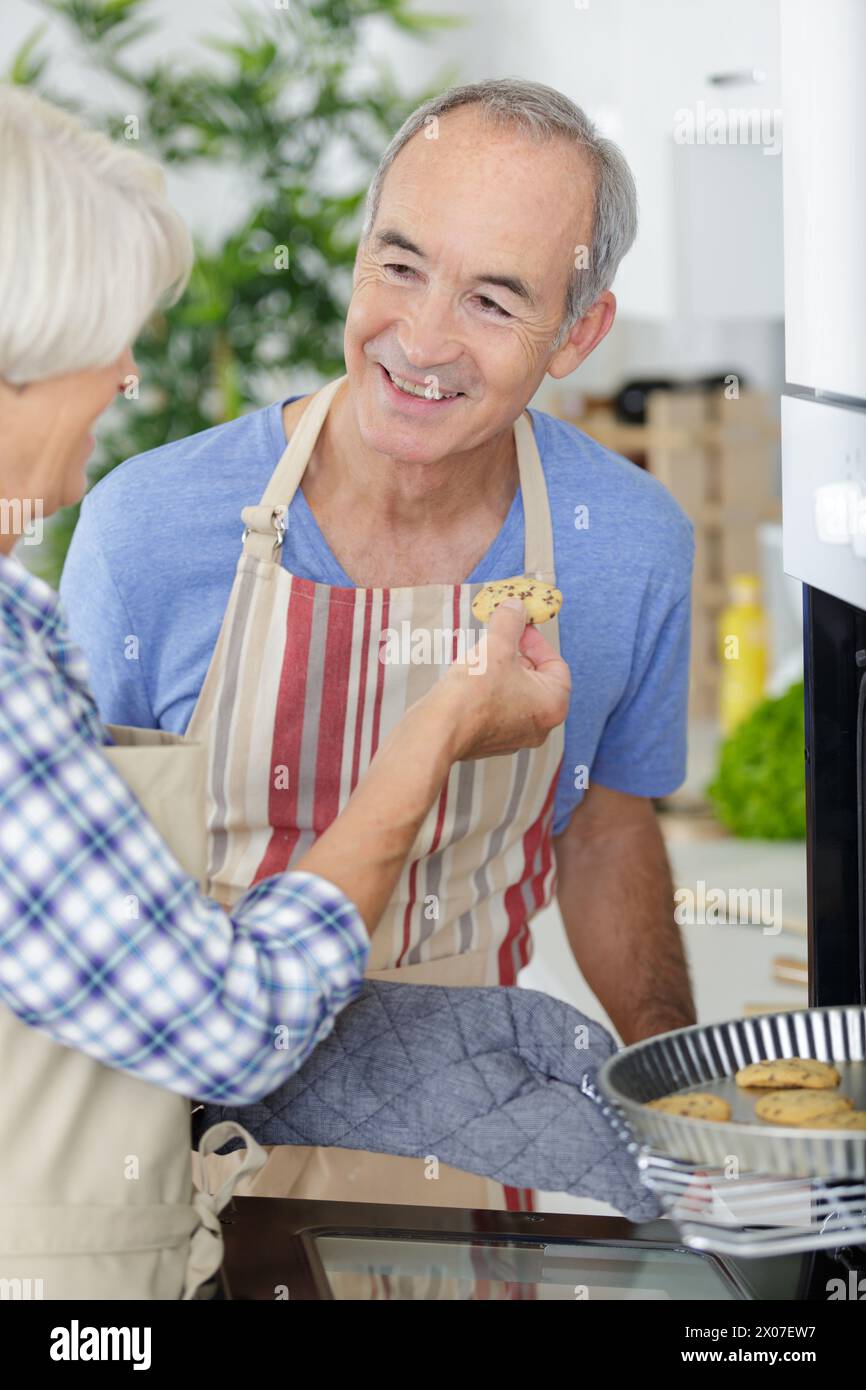 smiling elderly spouses enjoying tea with sweets Stock Photo