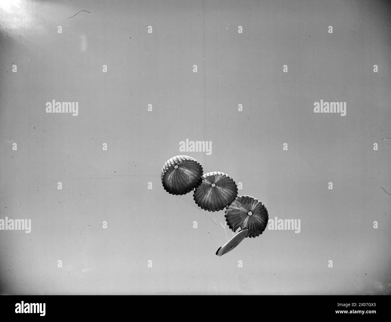 LIFEBOAT DROPPED FROM AIR. 13 JULY 1945, LEE-ON-SOLENT. THE DEMONSTRATION DROP OF THE NAVY'S AIRBORNE LIFEBOAT, 17 FT, 9 INS LONG, WHEN IT WAS DROPPED BY PARACHUTE TO AN AIR CREW WHO WERE SUPPOSED TO HAVE FORCED LANDED INTO THE SEA. THE LIFEBOAT, SELF-RIGHTING, AND SELF-BALING IS EQUIPPED WITH SAILS AND AN OUTBOARD ENGINE WHICH GIVES IT A RANGE OF 120 MILES AT 4 KNOTS. - The lifeboat held by three parachutes, dropping from the Fairey Barracuda Stock Photo