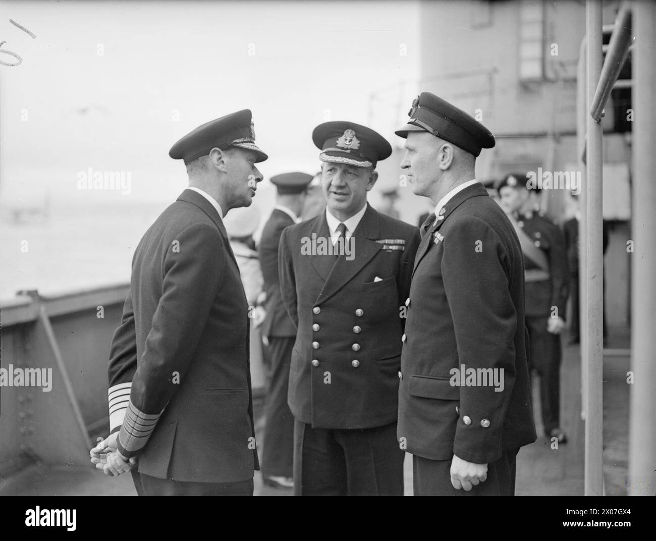 ROYAL VISIT TO HMS KING GEORGE V. 29 OCTOBER 1944, GREENOCK. THE KING AND QUEEN ACCOMPANIED BY PRINCESS ELIZABETH AND PRINCESS MARGARET PAID A FAREWELL VISIT TO THE BATTLESHIP HMS KING GEORGE V BEFORE SHE LEFT TO JOIN BRITAIN'S EAST INDIES FLEET. - The King chatting to Stoker Petty Officer R J Hugill, DSM, of Redcar, Yorks (right) who has been with the battleship since her launching. Centre is the Commanding Officer, Captain T E Halsey, DSO, RN Stock Photo