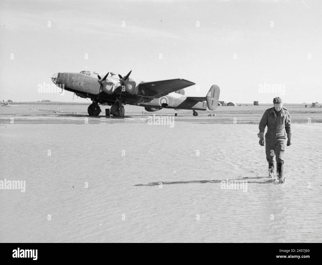 An RAF ground crew member of No. 614 Squadron walks through floodwater ...