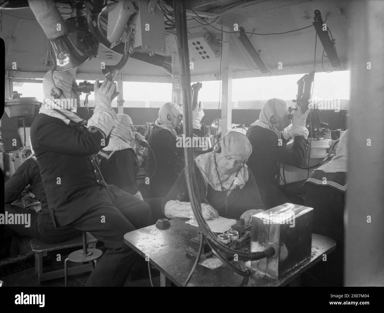 THE ROYAL NAVY DURING THE SECOND WORLD WAR - The scene inside the control tower on board HMS REVENGE. It is a tiny steel room perched high above the decks of the battleship where the brains behind the guns control the firing. Note the anti flash clothing being worn by the crew  Royal Navy, REVENGE (HMS) Stock Photo