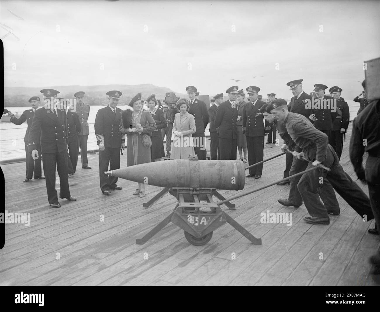 ROYAL VISIT TO HMS KING GEORGE V. 29 OCTOBER 1944, GREENOCK. THE KING AND QUEEN ACCOMPANIED BY PRINCESS ELIZABETH AND PRINCESS MARGARET PAID A FAREWELL VISIT TO THE BATTLESHIP HMS KING GEORGE V BEFORE SHE LEFT TO JOIN BRITAIN'S EAST INDIES FLEET. - The royal party watching a 14-inch shell being wheeled across the quarterdeck of the battleship Stock Photo